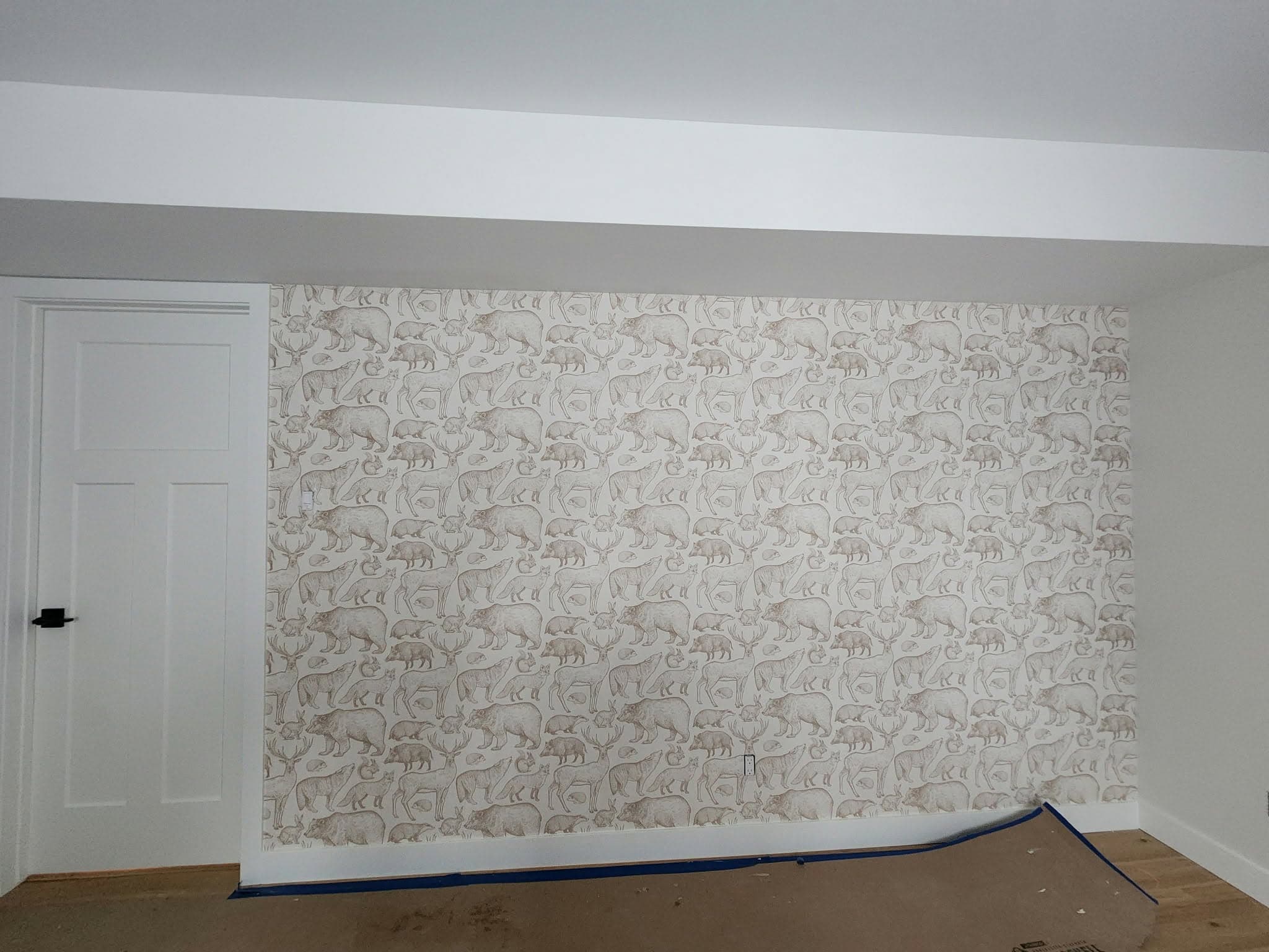 Papier peint à motif d'animaux de la forêt (ours, cerfs, renards) posé sur un mur d'accent
