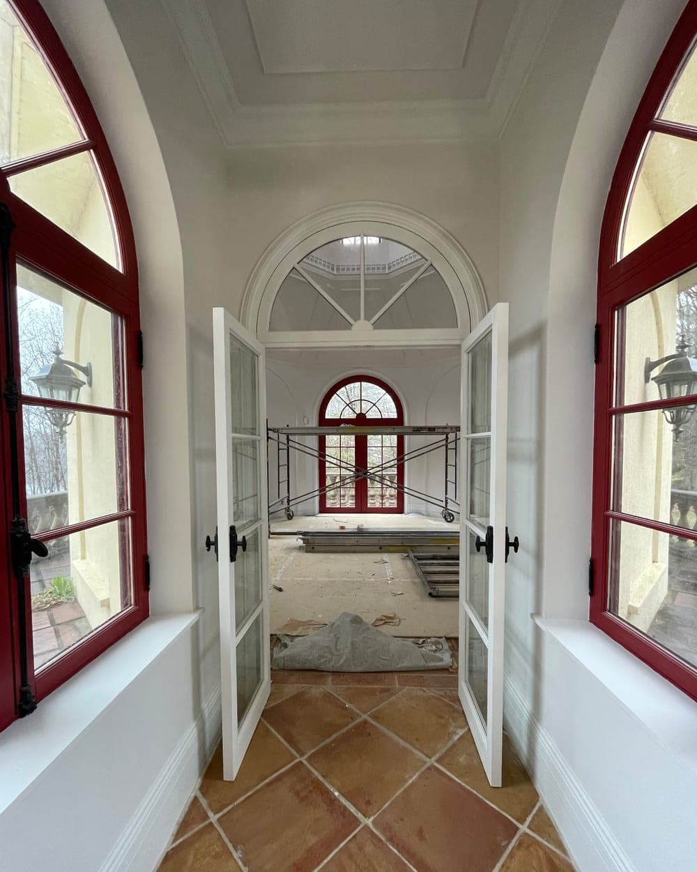 Couloir voûté aux portes-fenêtres cintrées rouges ouvrant sur le hall d'entrée